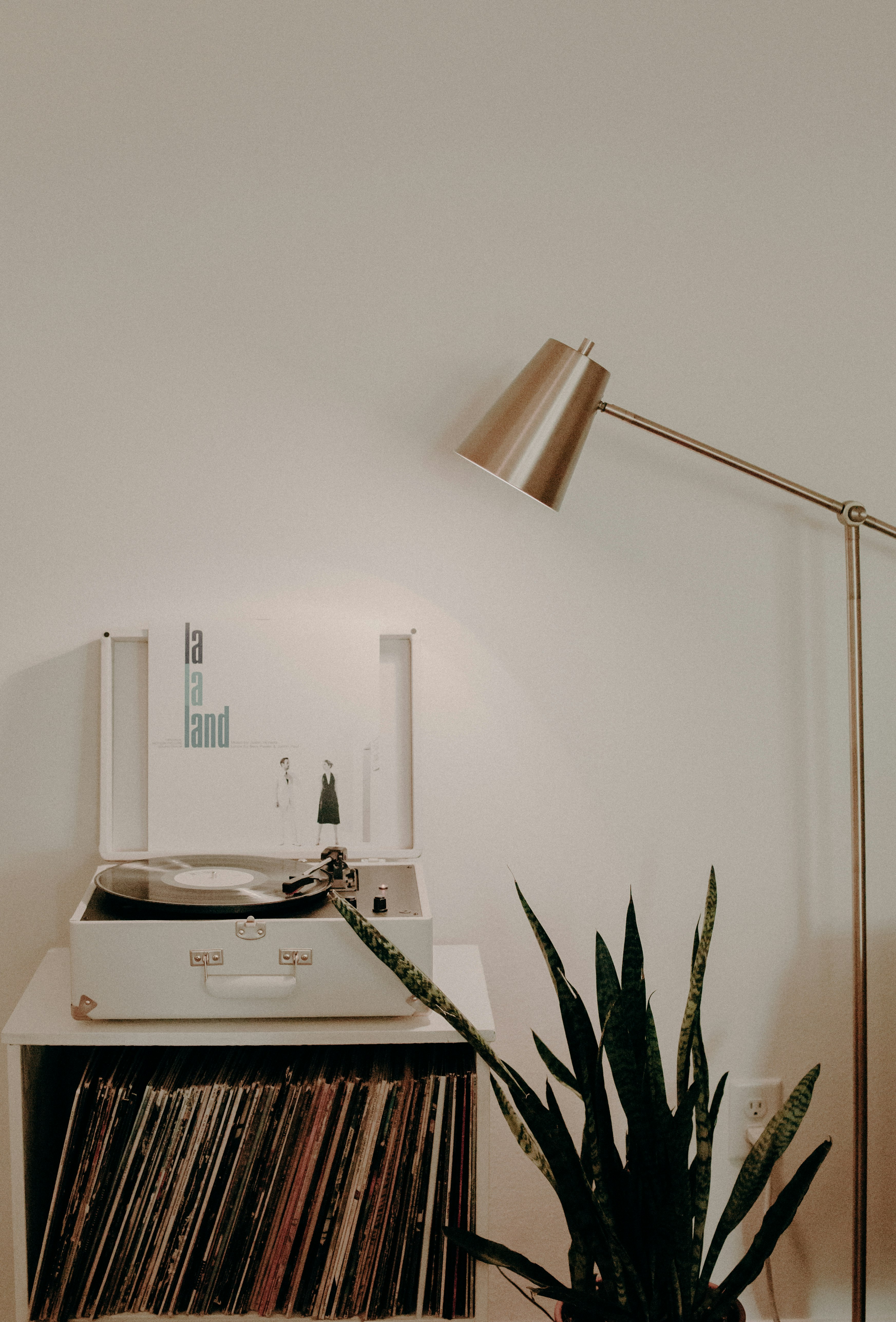 white turntable on white wooden organizer with vinyl record sleeves